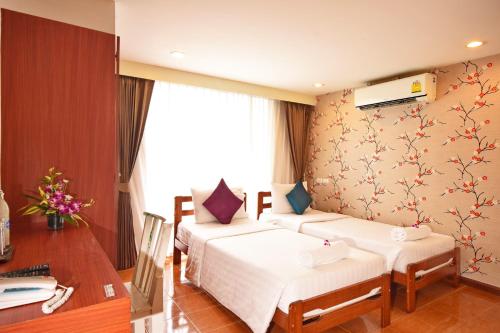 曼谷的住宿－拉查達畢莉斯酒店，酒店客房设有两张床、一张书桌和一个窗户。