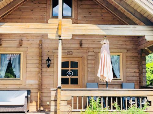 ein Holzhaus mit einer Veranda und einem Sonnenschirm in der Unterkunft Mountain Inn Chalets & Apartments in Walchsee