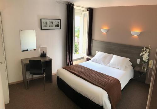 a hotel room with a bed and a desk and a window at Hôtel du Château in Alvignac