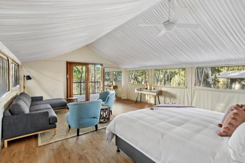 een slaapkamer met een bed en een bank en stoelen bij Sanctuary by Sirromet in Mount Cotton