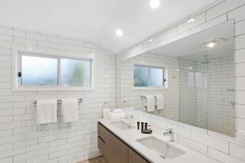 a white bathroom with a sink and a mirror at Sanctuary by Sirromet in Mount Cotton