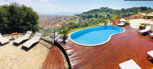 una piscina en una terraza de madera con sillas alrededor en Relais Villa Giuliana, en Licata