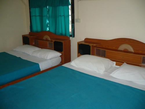 2 Betten in einem Schlafzimmer mit blauer Bettwäsche und weißen Kissen in der Unterkunft Mae Chaem Hotel and Resort in Mae Chaem