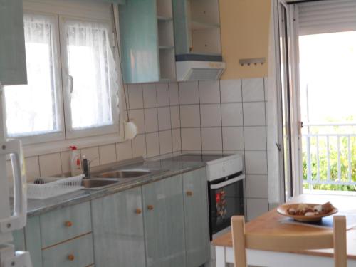una cucina con armadi grigi, tavolo e finestra di Sophies Apartments Ormos a Ormos Panagias