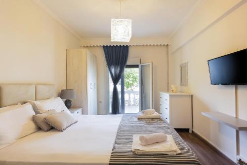 a bedroom with a large white bed with a flat screen tv at Despina House Ermones in Vátos