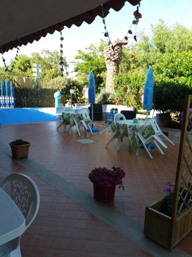 a patio with white chairs and tables and flowers at L'Artista B&B in Santa Lucia