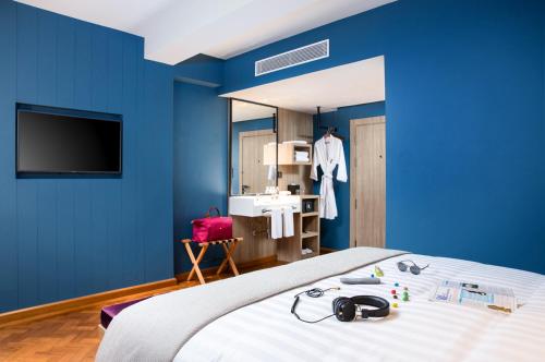 a blue room with a bed and a television at Hotel G Yangon in Yangon