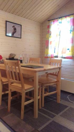 una mesa de madera y sillas en una habitación con 2 ventanas en JVT Cabins en Kiruna