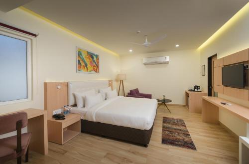 a hotel room with a bed and a flat screen tv at 10 Park Street Hotel & Banquets in Gorakhpur