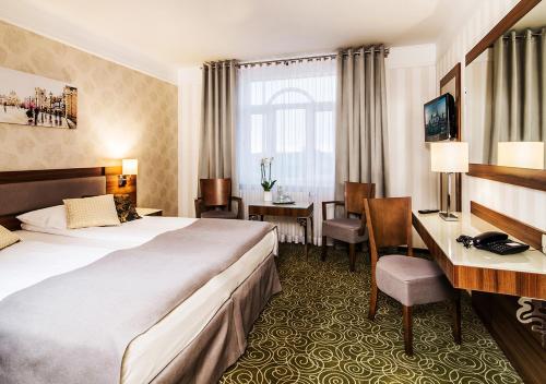 ワルシャワにあるHotel Lord - Warsaw Airportのベッドとデスクが備わるホテルルームです。