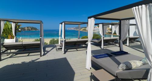 a deck with benches and the ocean in the background at H10 Casa del Mar in Santa Ponsa