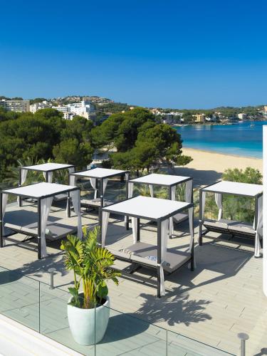 a group of tables and chairs on a patio with a beach at H10 Casa del Mar in Santa Ponsa
