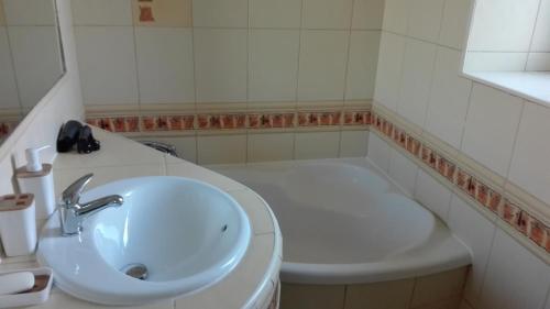 a white bathroom with a sink and a tub at Anna in Krynica Zdrój