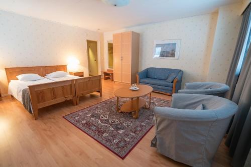 1 Schlafzimmer mit einem Bett, 2 Stühlen und einem Tisch in der Unterkunft Hotel Kievari in Ylitornio