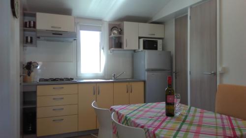 a kitchen with a table with a bottle of wine on it at Mobile Home Cinzia in Pula