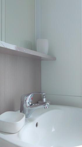 a bathroom sink with a faucet and a toilet at Mobile Home Cinzia in Pula