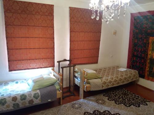una camera con due letti e un lampadario a braccio di Macedon Guest House a Barskoon