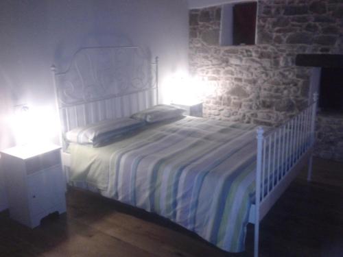 a bedroom with a white bed with a stone wall at Alloggio Agrituristico Conte Ottelio in Pradamano