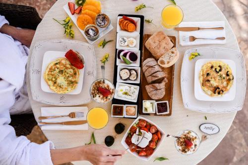 a table full of breakfast foods and orange juice at Cnaan Village Boutique Hotel & Spa in Had Nes