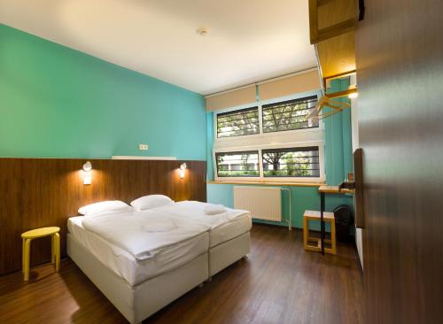 a bedroom with a white bed and a blue wall at Safestay Bratislava Presidential Palace in Bratislava