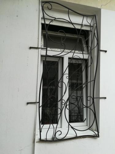 a window on a white building with a iron grate at Apartman Galerija in Novi Sad