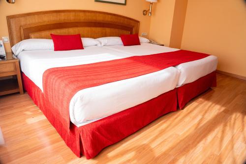 a bedroom with a large bed with red and white sheets at Senator Marbella in Marbella