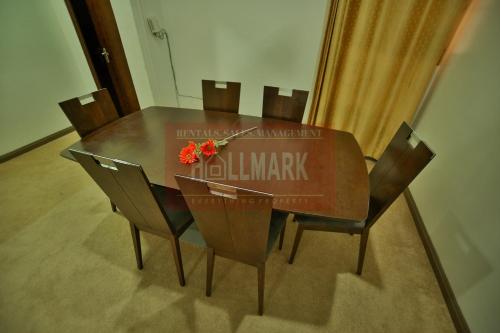 a dining room table with chairs and a clock on it at Hallmark Apartments -1 in Accra