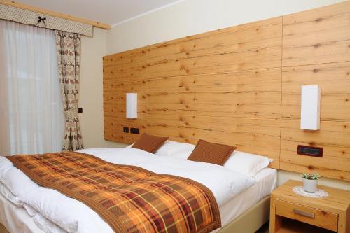 um quarto com uma cama grande e uma cabeceira em madeira em Residence Marisol Camere & Appartamenti - Mezzana Centre em Mezzana