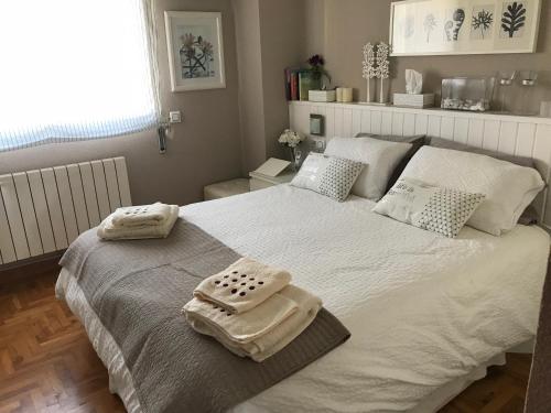 a bedroom with a large white bed with towels on it at Casa Castelao, parking gratuito in Vigo