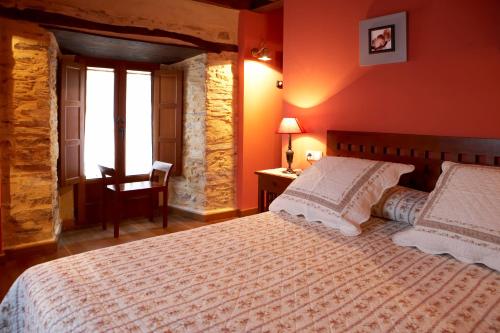 a bedroom with a bed and a table and a chair at Hotel Rural Casona Trabadelo in Vegadeo