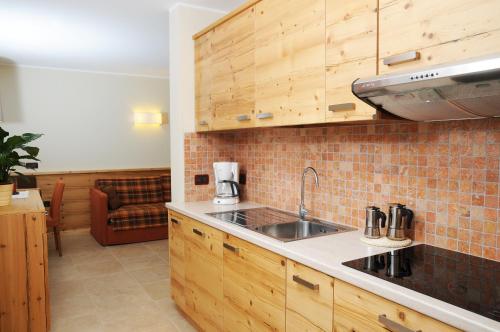 uma cozinha com armários de madeira e um lavatório em Residence Marisol Camere & Appartamenti - Mezzana Centre em Mezzana