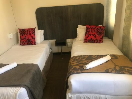 two beds in a hotel room with red pillows at Businessburg Hotel in Johannesburg