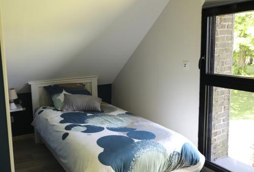 Una cama sentada en una habitación con ventana. en Gîte Le Clos de la Bertinière, en Bosgouet