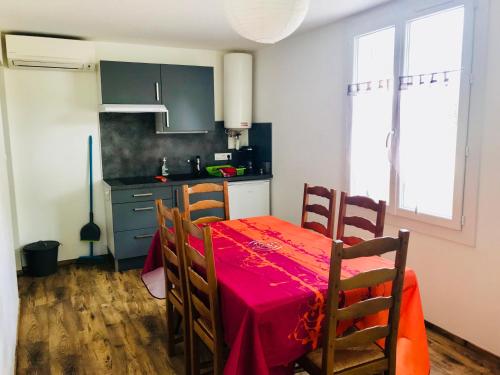 a kitchen with a table with a red table cloth at Chez marinette in Le Cailar