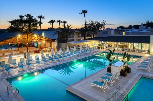 a pool with lounge chairs and a hotel at Hotel Vibra Cala Tarida-3SUP in Cala Tarida