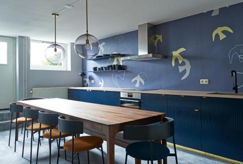 a kitchen with blue cabinets and a wooden table and chairs at Hotel Pistache Den Haag in The Hague