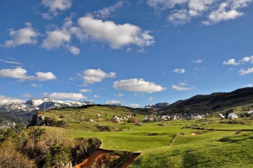 a village on a green hill with mountains in the background at Guesthouse Nedajno in Nedajno