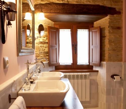 a bathroom with two sinks and two windows at Hotel Rural Casona Trabadelo in Vegadeo