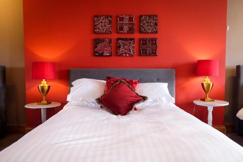 a bedroom with red walls and a white bed with two lamps at York House Durham in Durham