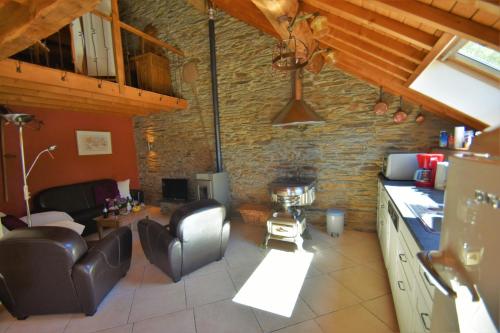 Gites-Clairiere-Ardenne في Louftémont: مطبخ وغرفة معيشة بجدار حجري