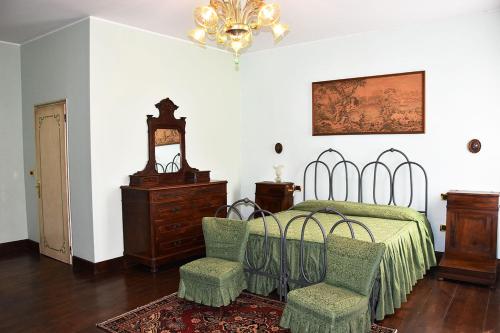 a bedroom with a bed with two chairs and a chandelier at Agriturismo Tenuta Goro Veneto in Ariano nel Polesine