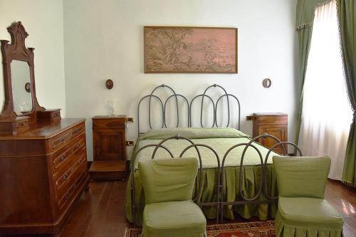 a bedroom with a bed and a dresser and chairs at Agriturismo Tenuta Goro Veneto in Ariano nel Polesine