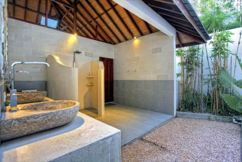 a bathroom with a stone sink and a shower at Villa Esperanto Seminyak in Seminyak