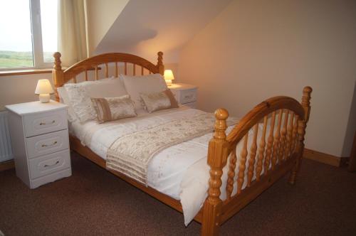 um quarto com uma cama de madeira, 2 mesas de cabeceira e uma janela em Southwind B&B em Spanish Point