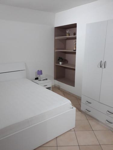 a white bedroom with a bed and a dresser at Barco Apartment in Ostuni