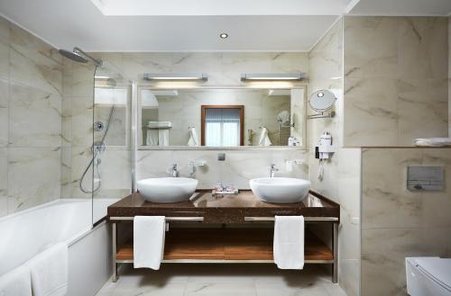 a bathroom with two sinks and a shower and a tub at Victoria & SPA Minsk in Minsk
