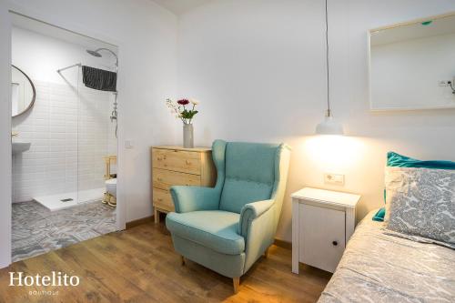 Un dormitorio con una silla azul junto a una cama en Hotelito Boutique Mercat, en Hospitalet de Llobregat