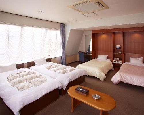 a hotel room with two beds and a table at Hotel Taira in Naha