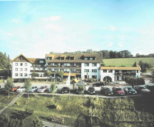 ein großes Gebäude mit Autos auf einem Parkplatz in der Unterkunft hotel zentlinde in Mossautal