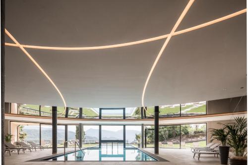 a large building with a pool and glass ceilings at Hotel Torgglhof in Caldaro
